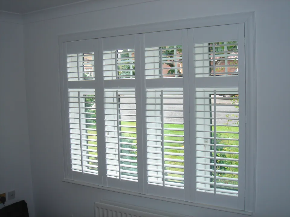 Full-height white wooden shutters fitted to a bay window in a southside Glasgow tenement living room